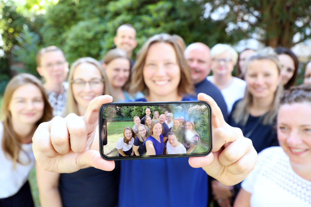 Selfie on mobile phone showing the team in the blurry background