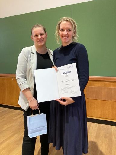 two women standing together and holding a certificate
