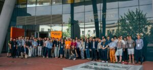 Eine Gruppe von ca. 70 Kongressteilnehmer:innen steht vor einem großen Glasfenster beim Gruppenfoto