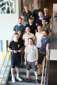 14 Personen stehen auf einer Treppe für ein Gruppenfoto