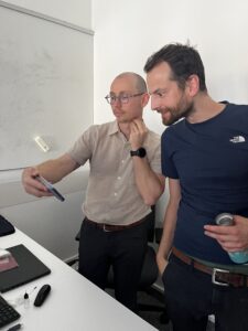 Zwei männliche Personen schauen fasziniert auf ein Bild am Handy