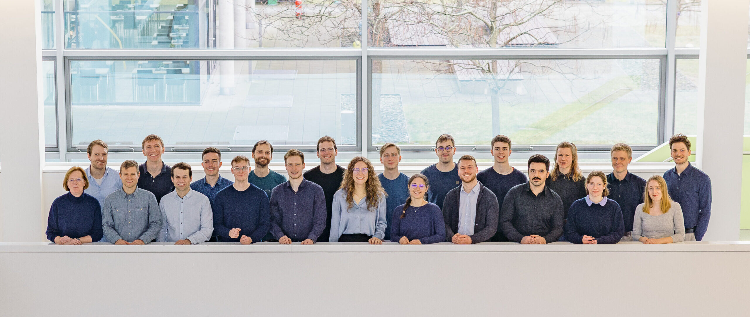 22 Personen stehen vor einer Balustrade für ein Gruppenfoto.