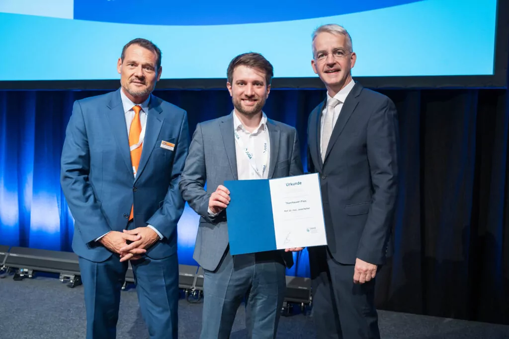 Prof. Kather mit Urkunde steht in der Mitte