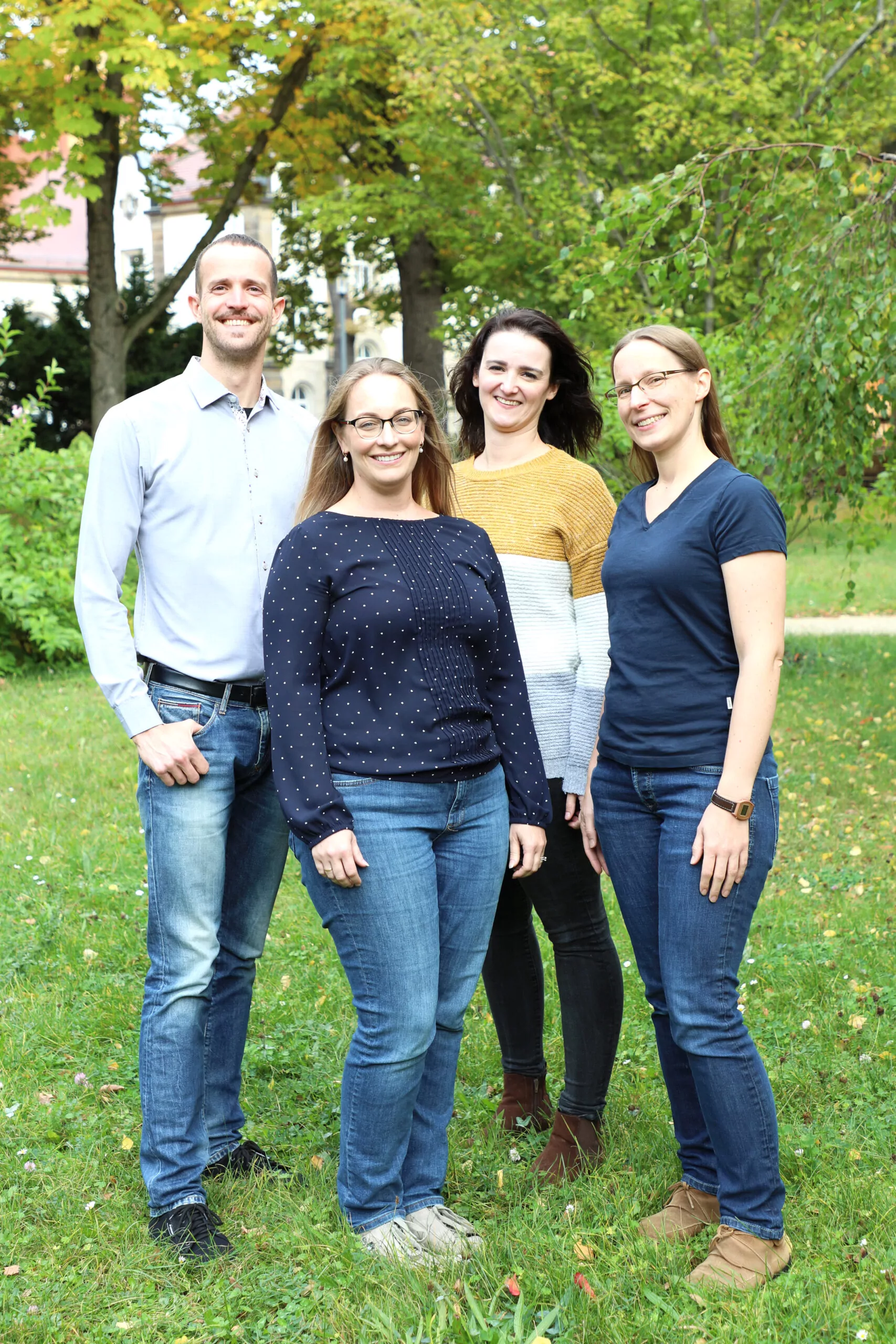 Team in the park: one man and three women standing together