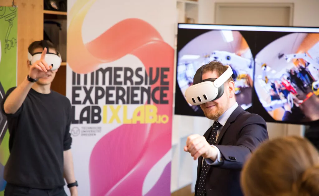 two men wearing VR glasses in the background the monitor is showing the VR scenario