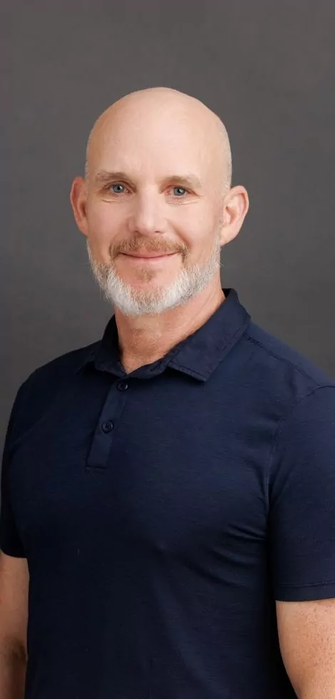 portrait of a man with a bald head, beard and blue shirt