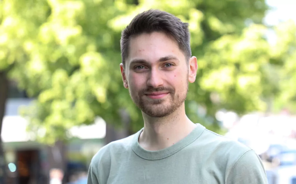 Young man in front of trees