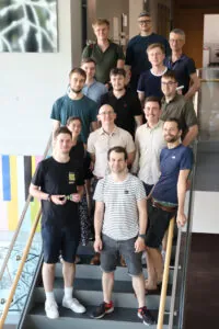 14 Personen stehen auf einer Treppe für ein Gruppenfoto