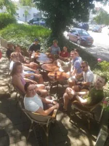 Auf dem Bild sieht man 12 Personen um einen Tisch herum sitzen